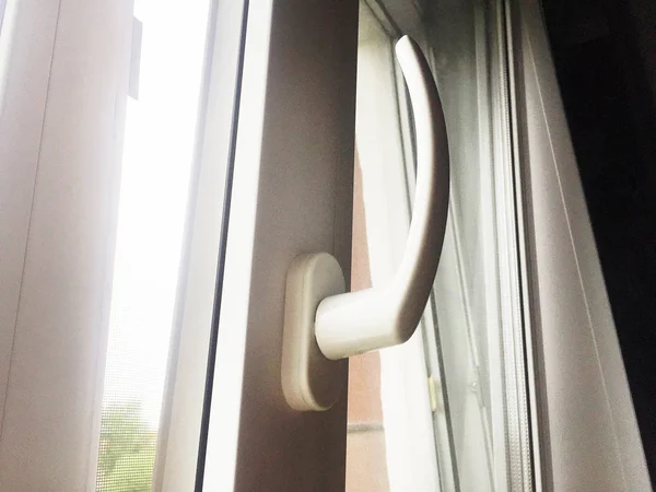 Open window. White PVC plastic. Handle on a plastic window close up.