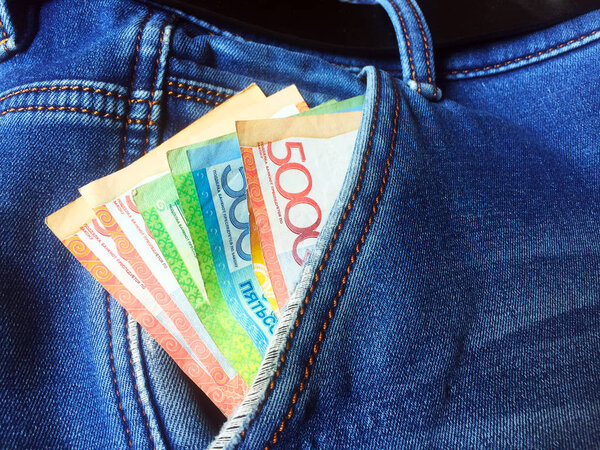 Banknotes of 500, 2000 and 5000 Kazakhstani tenge in the pocket of men's jeans. Money in your pocket. Close-up.