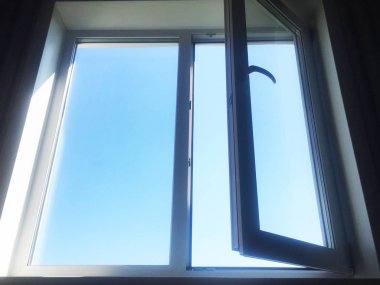 Pencereyi aç. Beyaz Pvc plastik. Pencerenin dışında mavi gökyüzü.