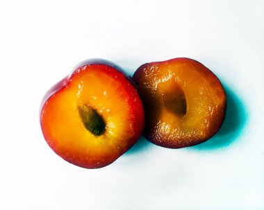 Beyaz bir arka plan üzerinde olgun sulu erik. Olgun eriki kemikle kes. Yakın çekim, izole.