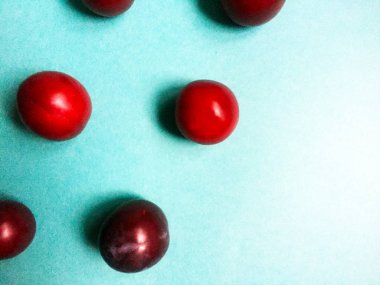 Düz mavi bir arka plan üzerinde olgun sulu erik. Farklı boyutlardaerik sırayla dizilmiş. Close.