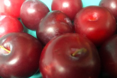 Düz mavi bir arka plan üzerinde olgun sulu erik. Yakın çekim, üst görünüm.