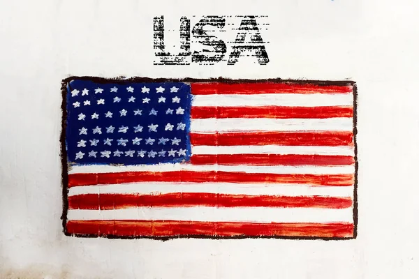 The national flag of the USA, painted on an old white concrete wall. Graffiti on a white wall.