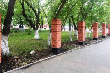 Kırmızı tuğla sütunlar. Parkta bir çit inşa etmeye başla. Tuğla.