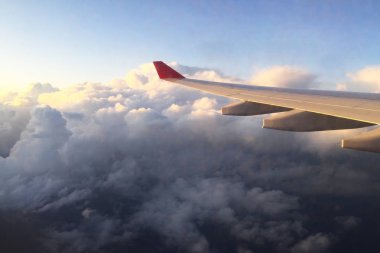 Bir aydınlatıcının penceresinden uçak kanadı. Bulutların üzerinde uçuyor. Close.