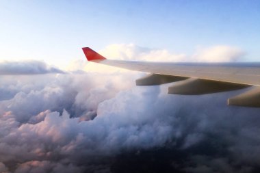 Bir aydınlatıcının penceresinden uçak kanadı. Bulutların üzerinde uçuyor. Close.