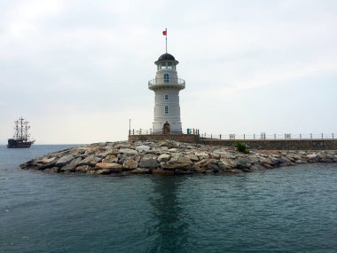 Güzel derin deniz ve beyaz bir yüksek deniz feneri. Akdeniz'de bir gemi veya yat ta yolculuk. Skyline.