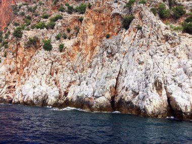 Akdeniz kıyılarında küçük dalgalar ve sarp kayalıkları olan güzel derin deniz. Ağaçları ve mağaraları olan. Kayalık sahil boyunca bir gemi ya da yat ile güzel bir doğa ile deniz yolculuğu..