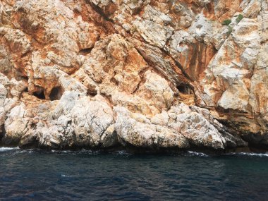 Akdeniz kıyılarında küçük dalgalar ve sarp kayalıkları olan güzel derin deniz. Ağaçları ve mağaraları olan. Kayalık sahil boyunca bir gemi ya da yat ile güzel bir doğa ile deniz yolculuğu..