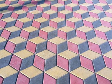 Şehir parkında geniş bir yol. Gri, pembe ve sarı döşeme karoları geometrik bir desen ile kaplıdır. Arka plan ve doku.