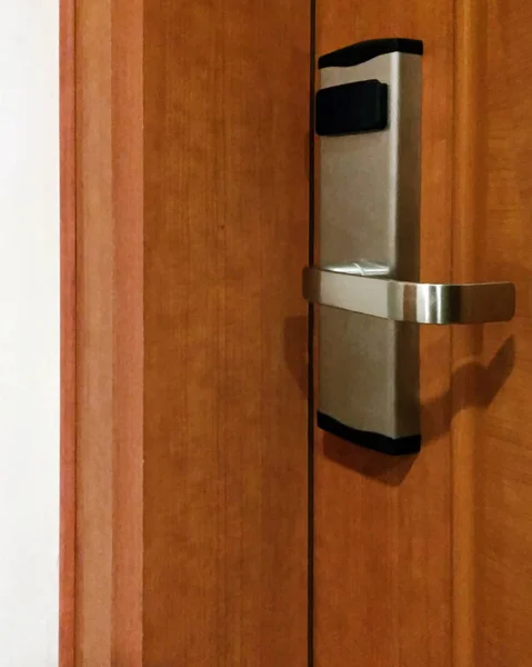 A lock with a metal handle and a card reader on a wooden door. Close-up.