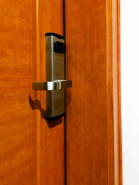 A lock with a metal handle and a card reader on a wooden door. Close-up.