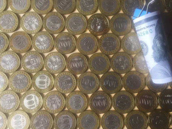100ドル紙幣が巻き上げ ペーパークリップで固定され 100カザフスタンテンゲの硬貨に載っています 背景とテクスチャ クローズ アップ — ストック写真