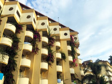 Hafif duvarlar, zarif balkonlar ve bitkiler etrafında ile güzel bir çok katlı bina. İnşaatta ilginç bir mimari çözüm. Close.