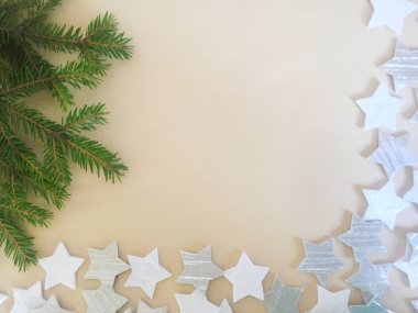 Beyaz ve gümüş yıldız figürleri ve hafif bir arka plan üzerinde küçük iğneler ile yeşil ladin bir dalı. Noel ve Yeni Yıl konsepti. Arka plan ve doku. Close. Kopyalama alanı.