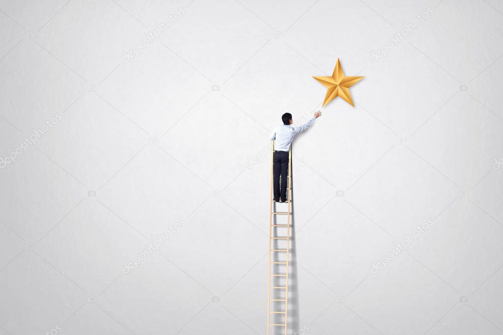 businessman climb on ladder to reach star goal