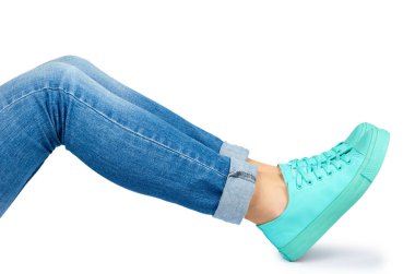 Kot pantolon ve spor ayakkabı beyaz arka plan üzerinde izole kadın bacak.