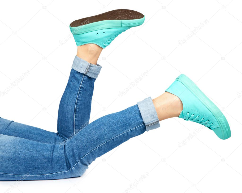 Female leg in jeans and sneakers isolated on white background.