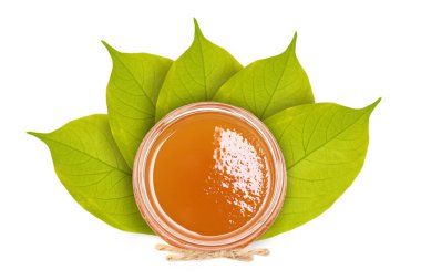 Yaprakların arka planda bir cam kapta taze tatlım. Beyaz izole.