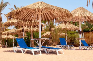 Güneş koruma ve kumlu plajda şezlong şemsiye.