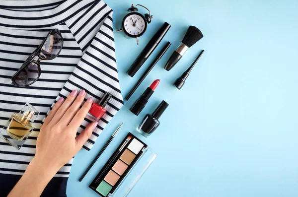 Composición de diferentes productos de maquillaje con mano sobre fondo azul — Foto de Stock