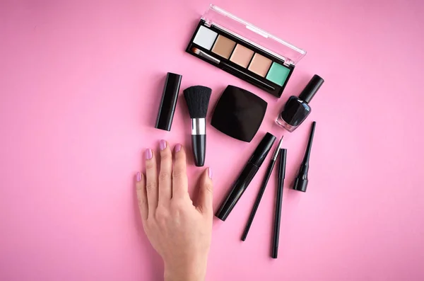 Composición de diferentes productos de maquillaje con mano sobre fondo rosa — Foto de Stock