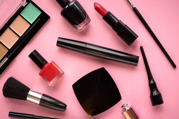 Pembe arka planda farklı makyaj ürünleri kompozisyonu