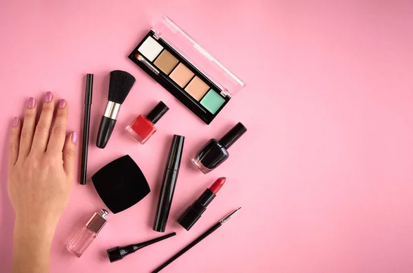 Composición de diferentes productos de maquillaje con mano sobre fondo rosa —  Fotos de Stock