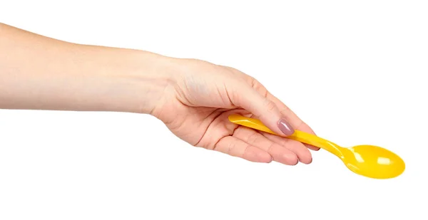 Mano con cuchara de plástico amarillo, utensilio desechable . —  Fotos de Stock
