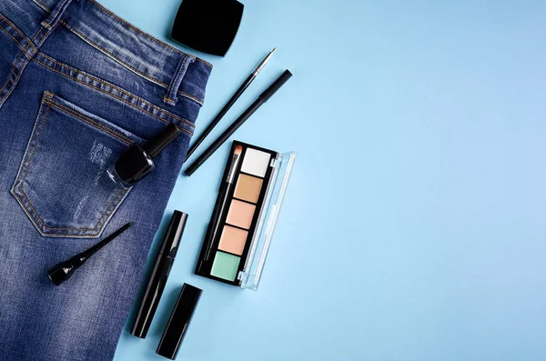 Komposition verschiedener Make-up-Produkte mit Jeans auf blauem Hintergrund — Stockfoto