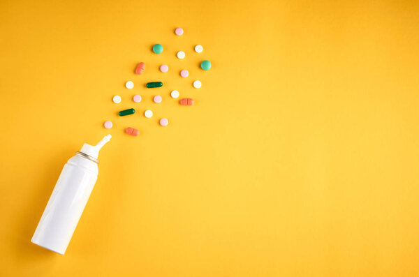 Бутылка из-под спрея для носа с составом таблеток, бутылка белого цвета на желтом фоне
