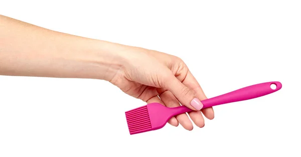 Mano con cepillo culinario rosa, utensilio de cocina . — Foto de Stock