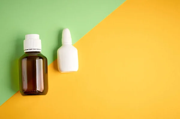 Burun sprey şişe kompozisyon, sarı ve yeşil arka plan üzerinde beyaz şablon şişe — Stok fotoğraf