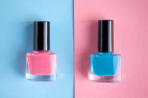 Color nail polish bottles on pink background composition.