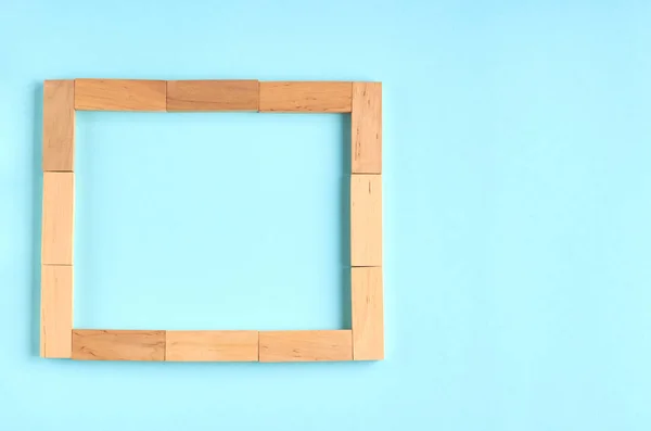 Brown wooden blocks frame shape idea on blue background composition. — Stock Photo, Image
