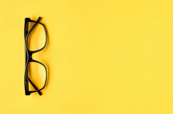 Gafas negras sobre fondo amarillo composición, gafas graduadas . — Foto de Stock