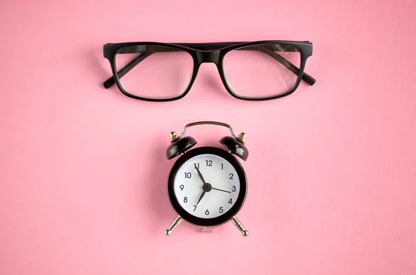 ピンクの背景構成に黒いメガネと目覚まし時計. — ストック写真
