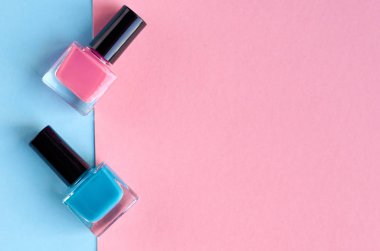 Pembe arka plan kompozisyonu üzerinde renkli oje şişeler.