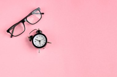 Siyah gözlük ve çalar saat pembe arka plan kompozisyon.