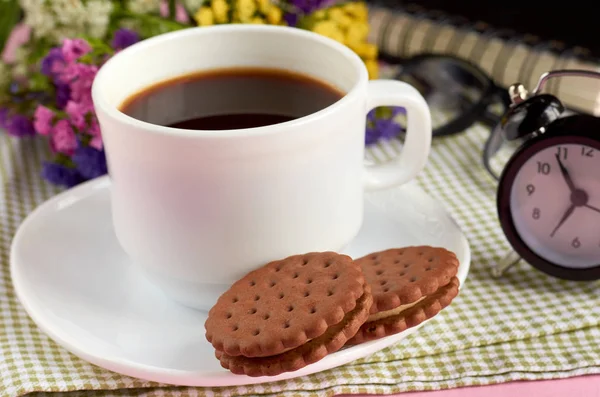 Tasse à café avec biscuits, réveil, fleurs, mascara, sur fond rose composition . — Photo