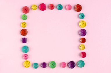 Pembe arkaplanda renkli dikiş düğmeleri bileşimi.