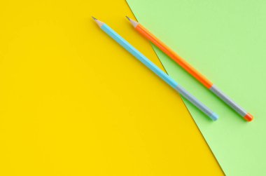 Sarı ve yeşil arkaplanda renkli kalemler kompozisyonu.