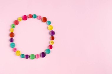 Pembe arkaplanda renkli dikiş düğmeleri bileşimi.