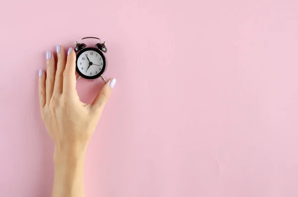 Mão com composição de despertador analógico no fundo rosa . — Fotografia de Stock