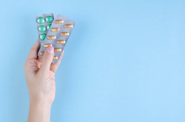 Mavi arka planda hap bileşimi olan bir el..