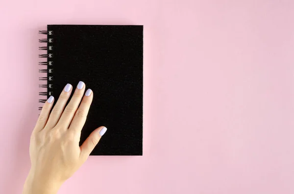 ピンクの背景にノートパッドの組成物と手. — ストック写真