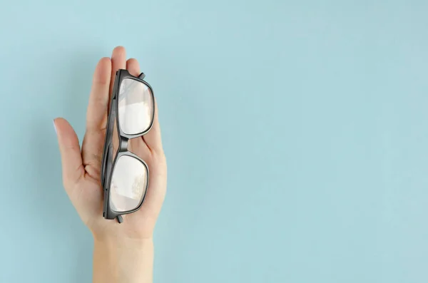 Hand med glasögon sammansättning på blå bakgrund. — Stockfoto