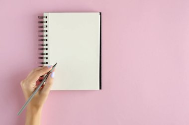 Pembe arka planda not defteri kompozisyonu olan el.