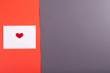 Koyu arkaplanda kırmızı kalp kompozisyonu olan kağıt zarf.