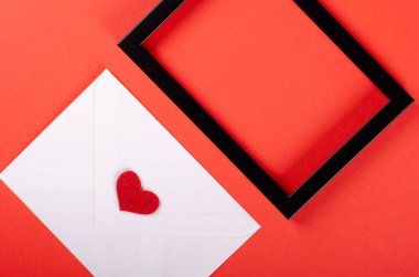 Kırmızı zemin üzerinde kırmızı kalp kompozisyonu olan kağıt zarf.